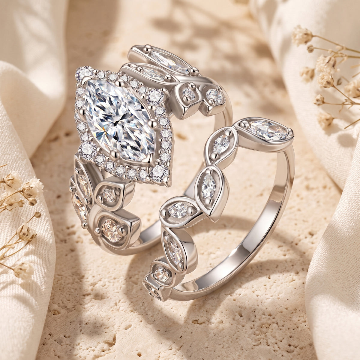 Close-up of a marquise simulated diamond halo ring and matching leaf-motif band in sterling silver.
