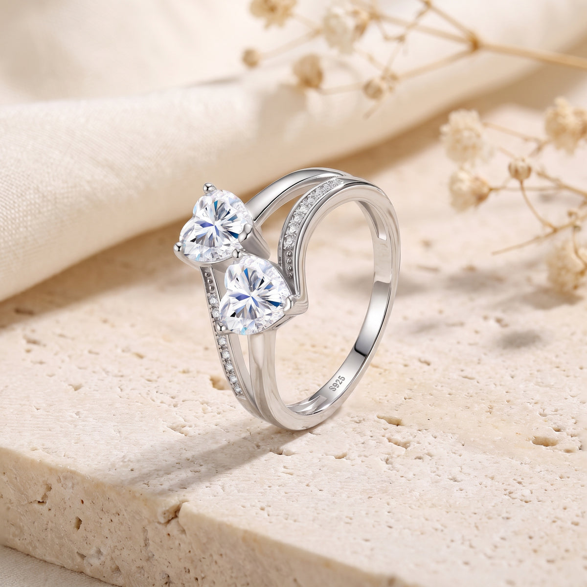 Angled view of the silver twin heart bypass ring on stone, showing the S925 stamp inside the band.