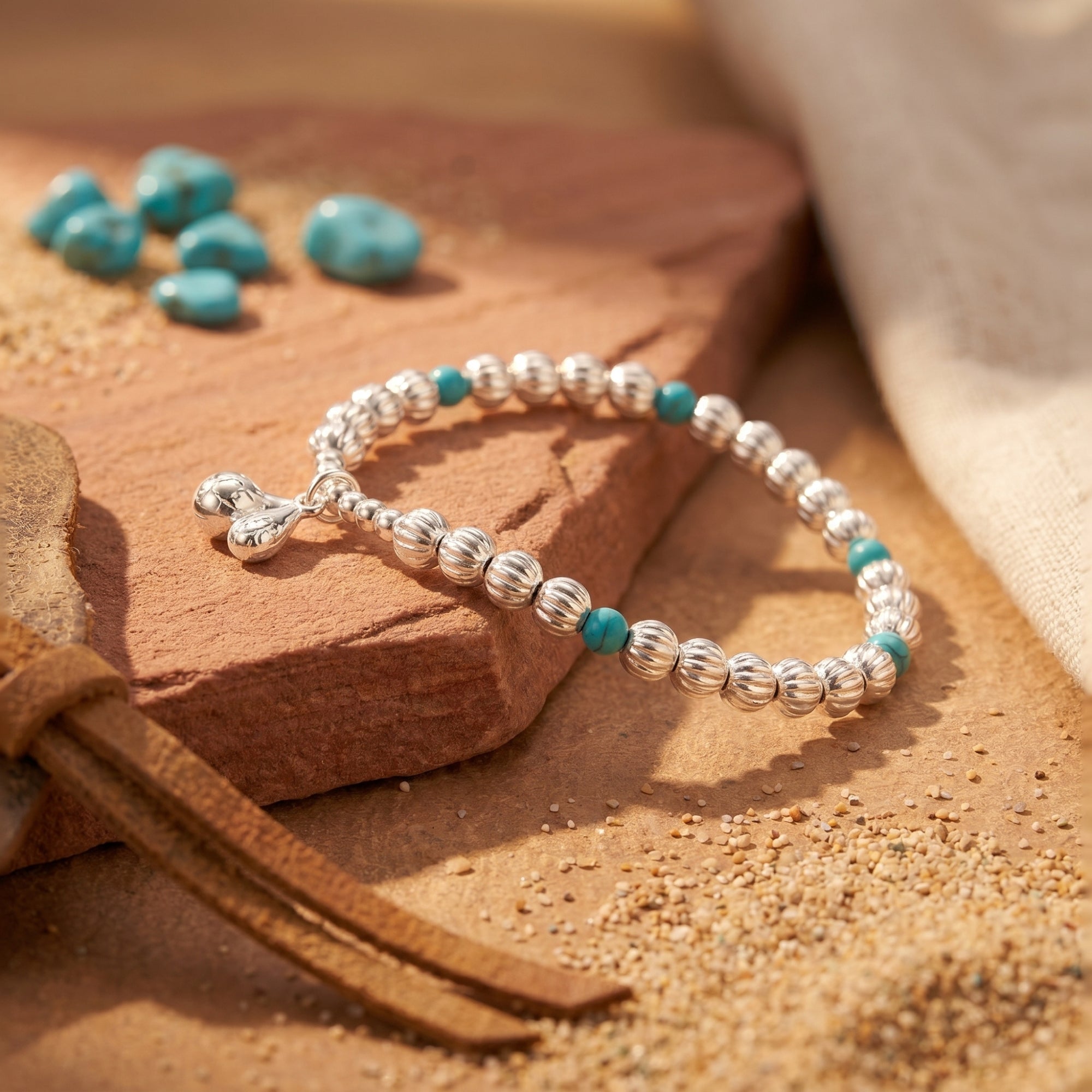 Detail of sterling silver fluted beads and turquoise stones on a Navajo-style charm bracelet.