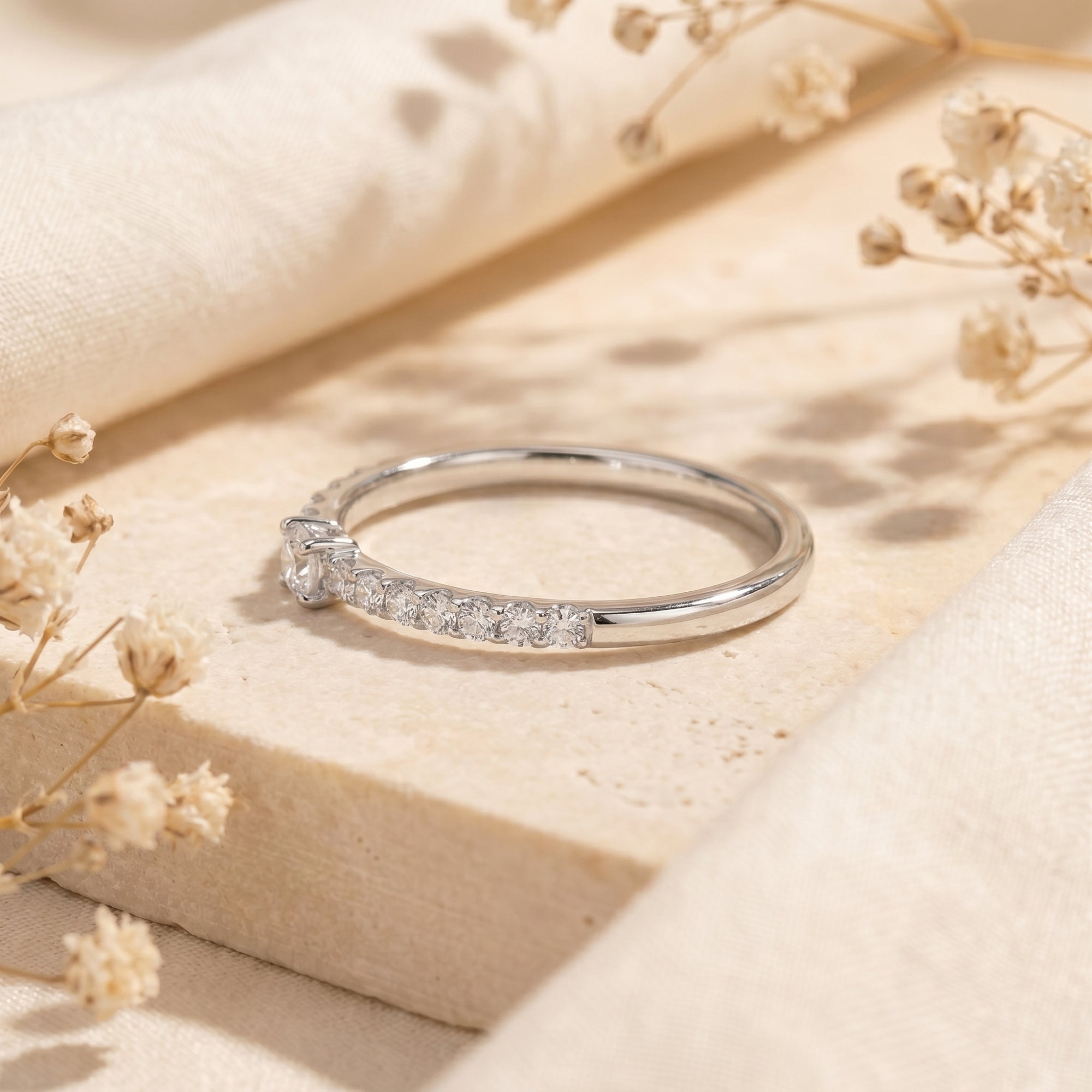 Side profile of a round moissanite solitaire ring in sterling silver showing pavé band details.