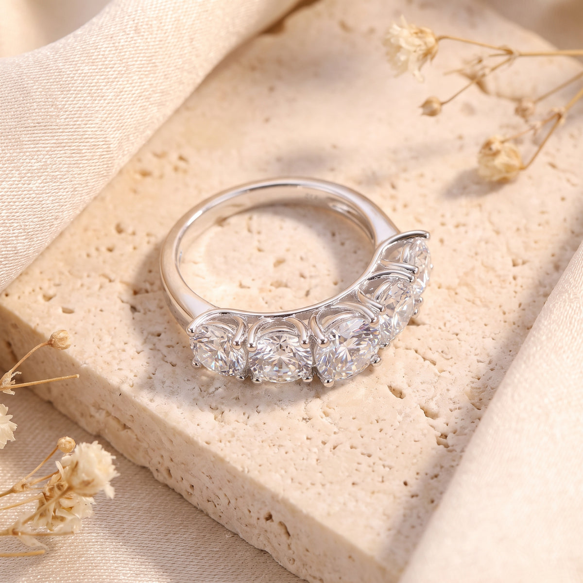 Top view of the Claralise sterling silver ring with five graduated round-cut simulated diamonds on a stone background.