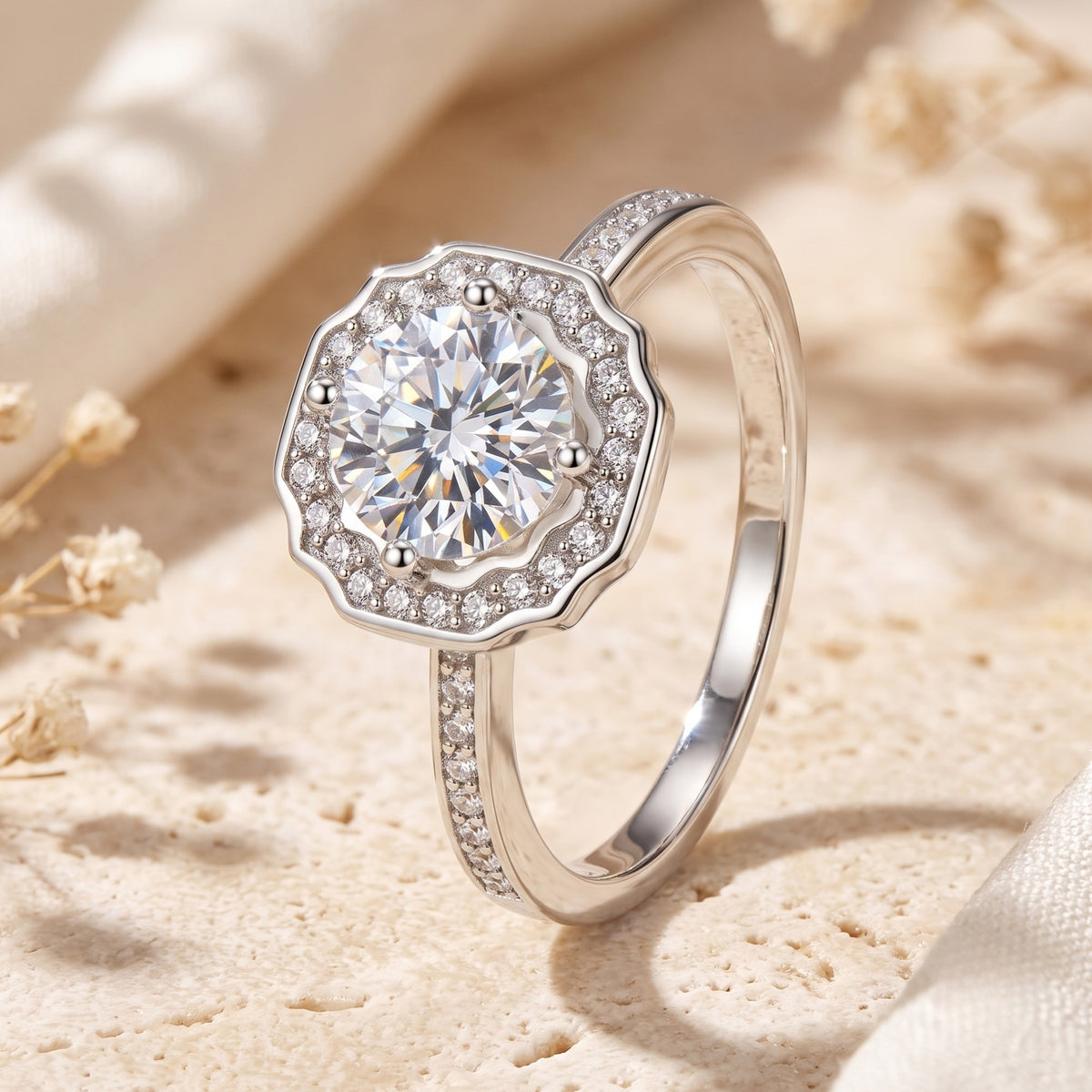 Three-quarter view of the silver ring on a textured stone surface, showing its scalloped halo and pave band.