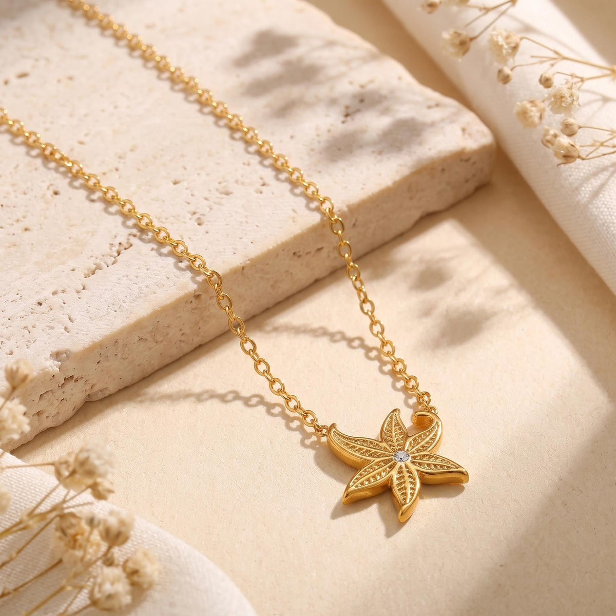 Detailed macro view of the gold starfish pendant with a round crystal and textured stainless steel finish.