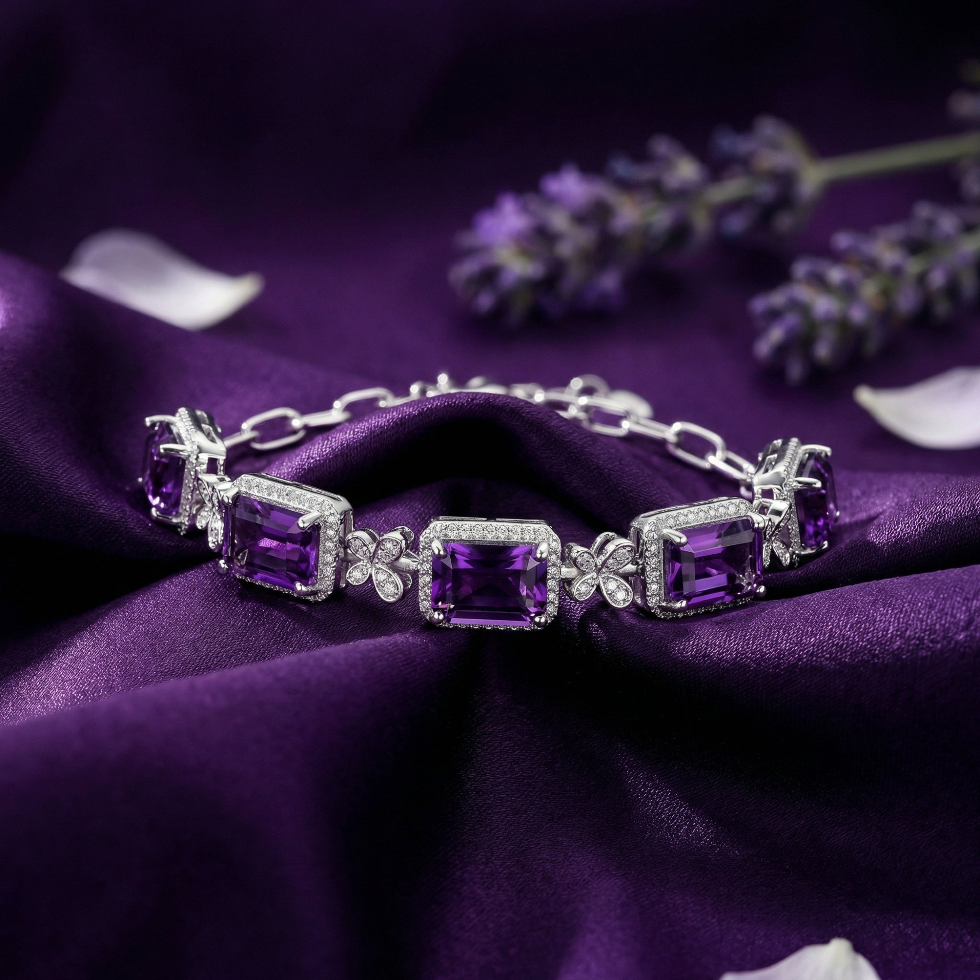 Close-up of square cut natural amethysts in S925 sterling silver prong settings on purple silk fabric.