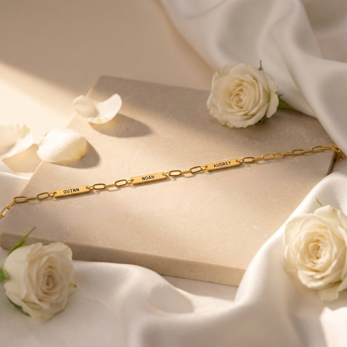 Close-up of gold stainless steel name bars Quinn, Noah, and Audrey on chain.