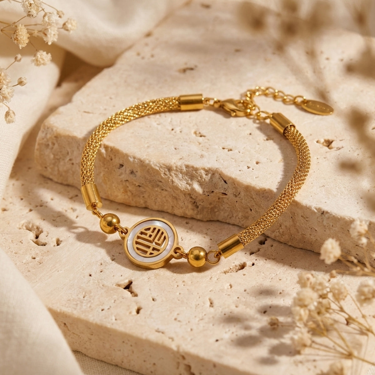 Angled view of the gold-tone mesh bracelet featuring a circular symbol medallion on light stone.