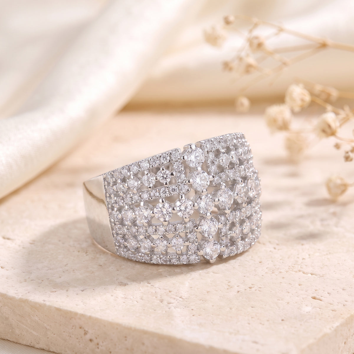 Detailed view of the silver lattice ring resting on a stone surface, featuring multi-row clear stone accents.