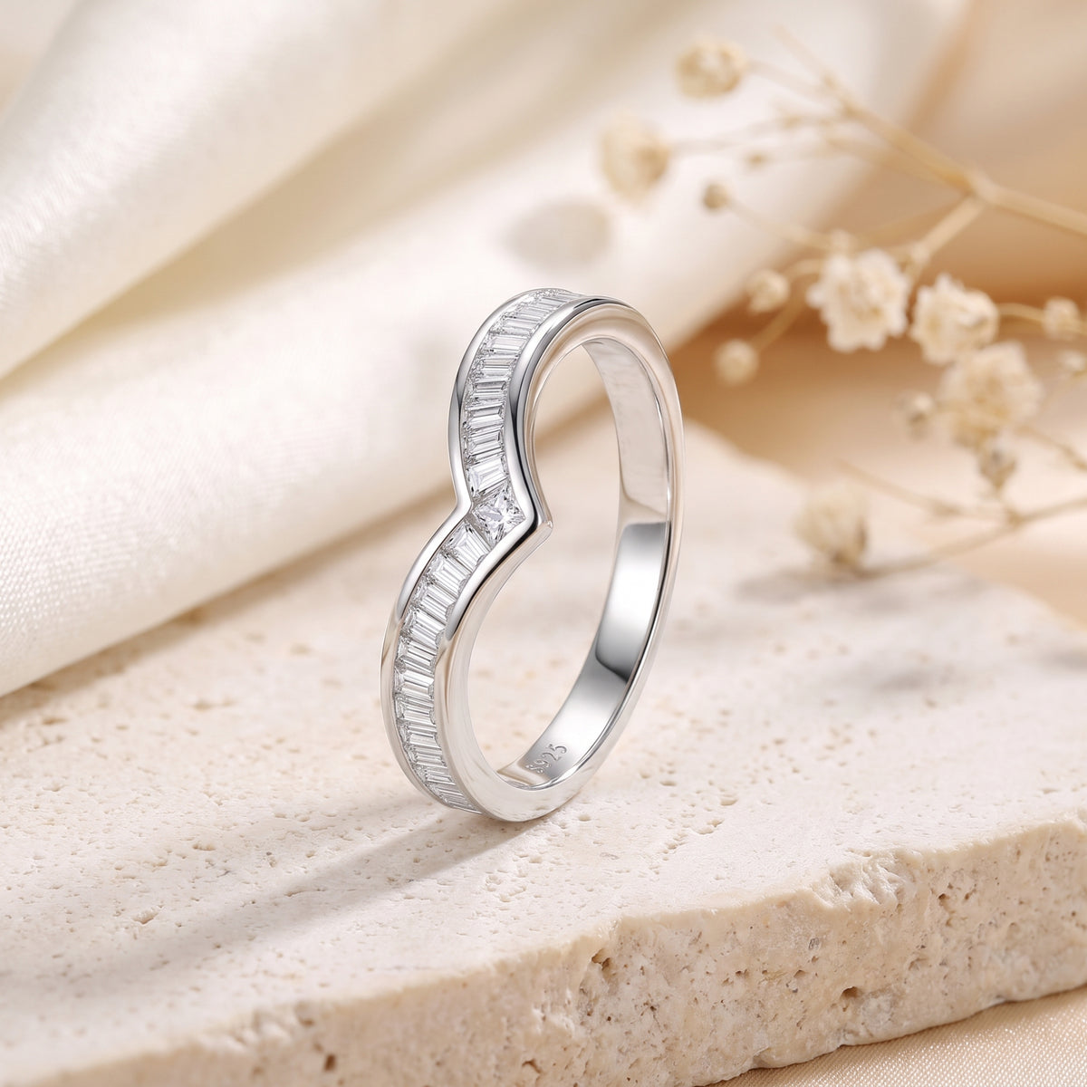 Upright view of a silver chevron ring with baguette stones and an S925 hallmark on the inner band.