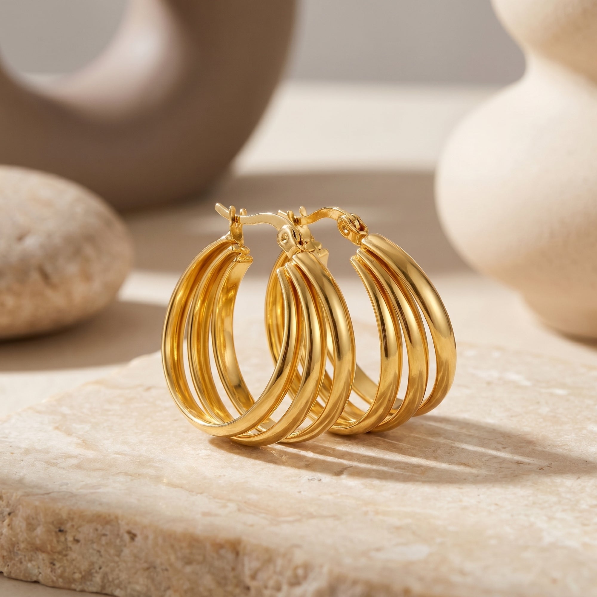 Macro view of gold triple-row woven hoop earrings showing the layered design.