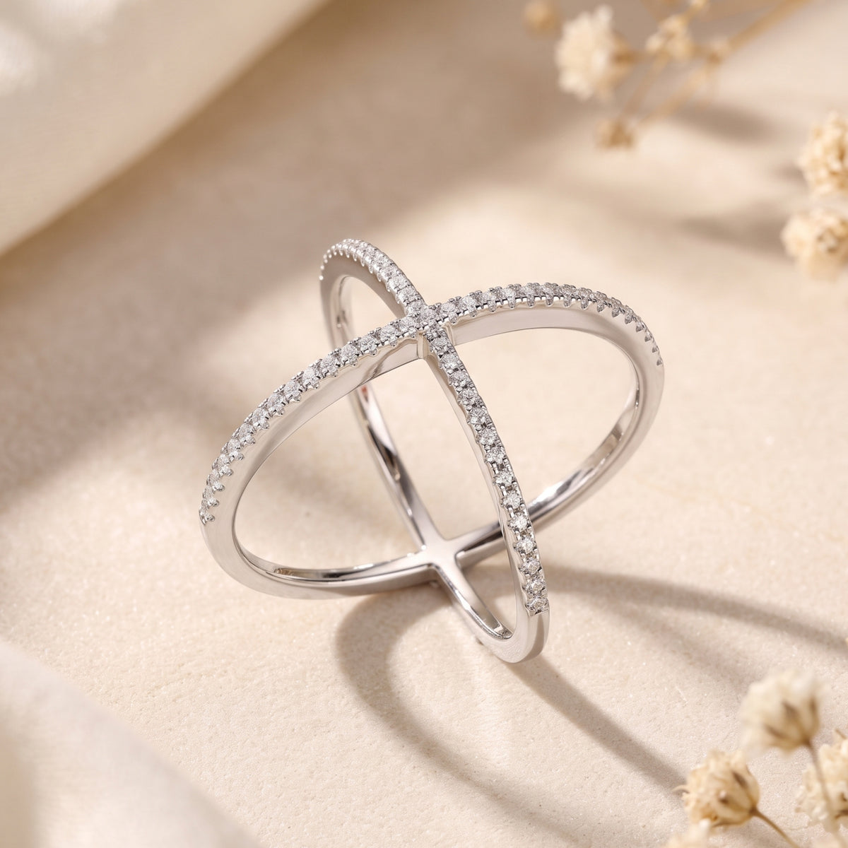 Angled view of the silver criss-cross ring, highlighting its overlapping structure lined with sparkling pavé stones.