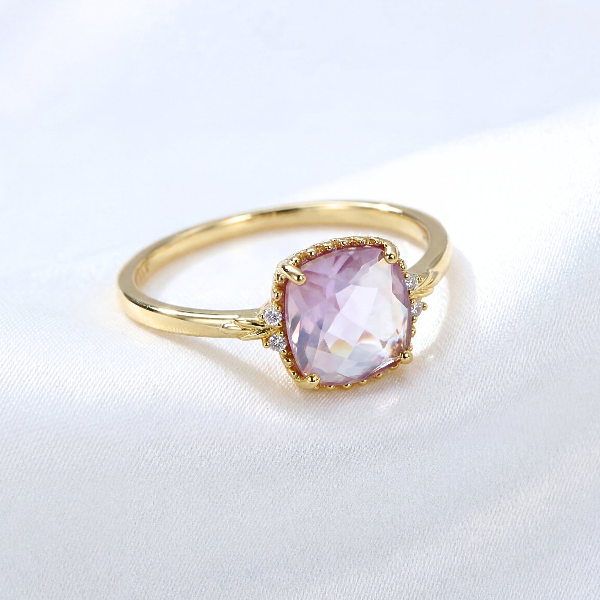 Cushion cut simulated amethyst solitaire ring in 18K gold vermeil shown on white fabric.