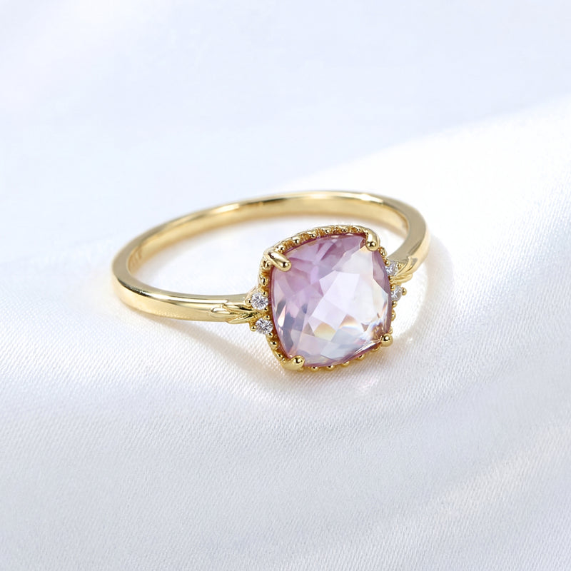 Cushion cut simulated amethyst solitaire ring in 18K gold vermeil shown on white fabric.