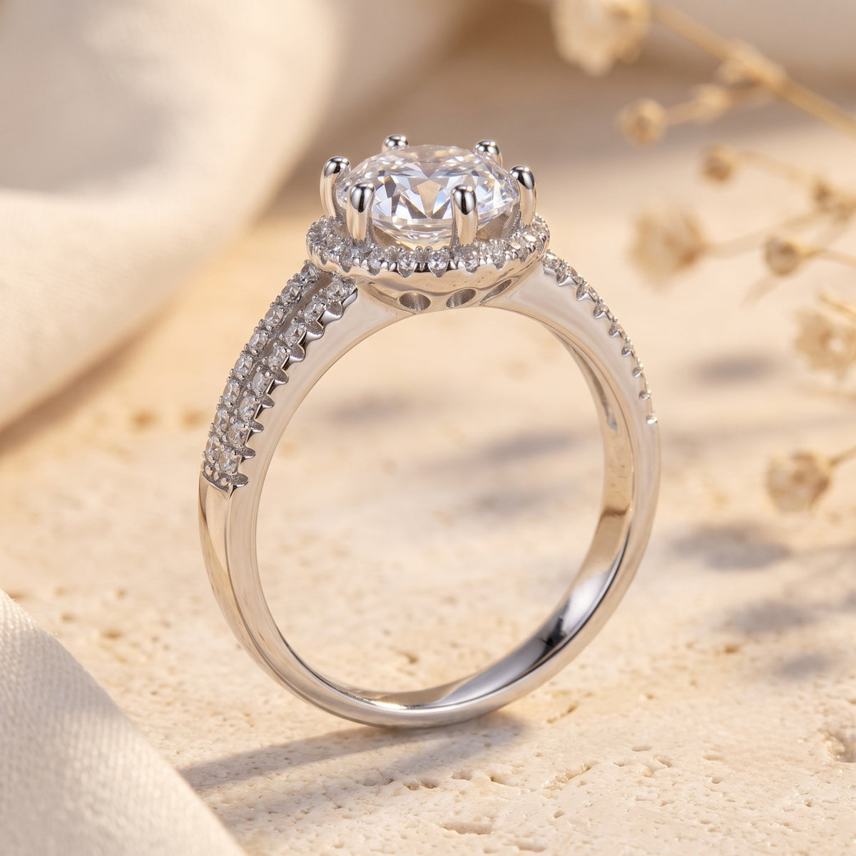 Side profile of the silver ring showing its elevated halo setting, prongs, and pavé stones along the upper band.