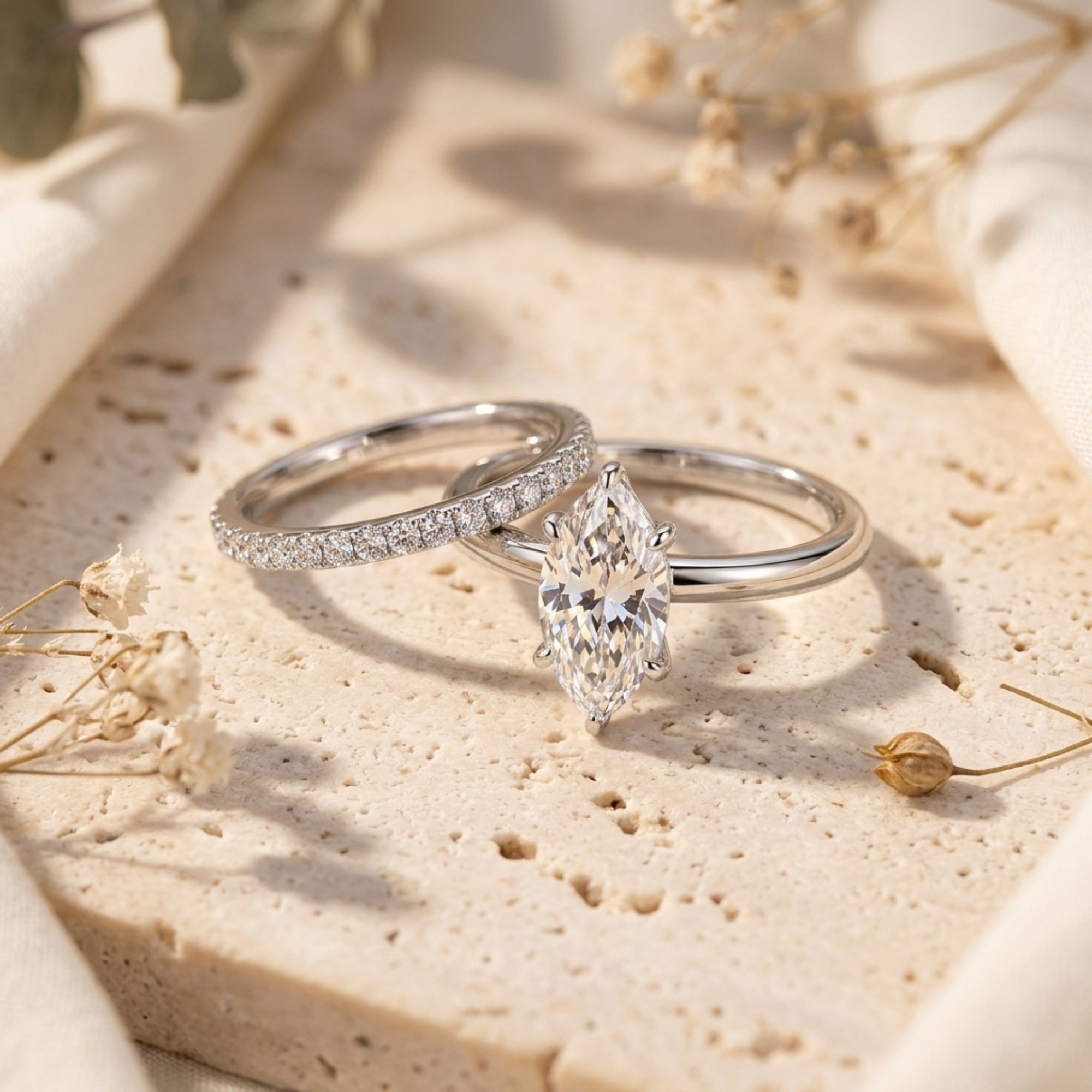 Close-up of a marquise cut simulated diamond and pavé band set in sterling silver on a textured stone.
