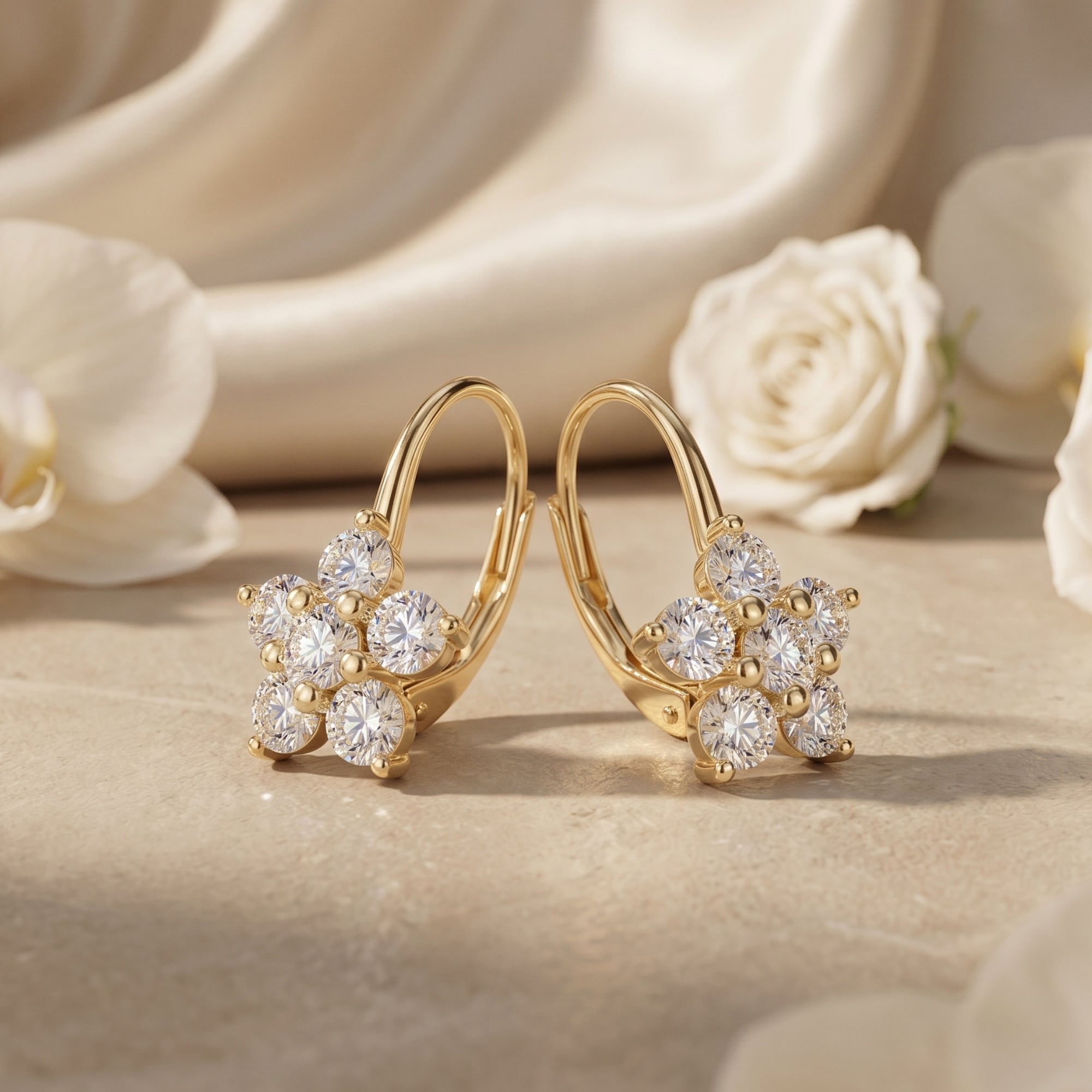 Gold floral moissanite drop earrings on stone with silk and roses.