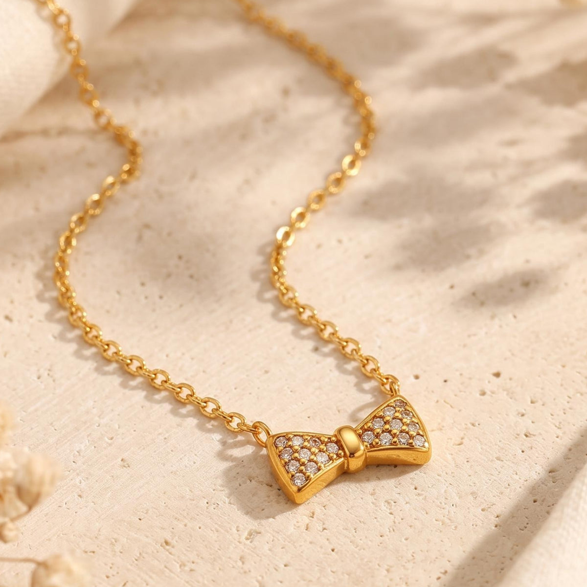 Close-up view of the gold-tone bow pendant decorated with sparkling pave-set clear cubic zirconia.