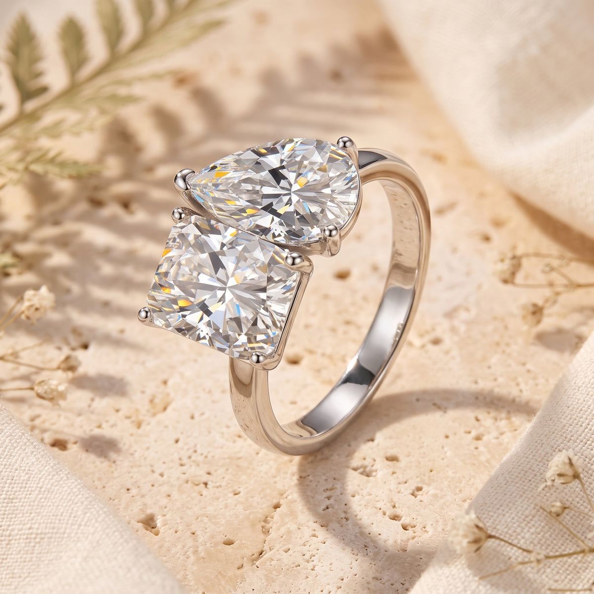 Macro view of a silver Toi et Moi ring with pear and radiant cut simulated diamonds.