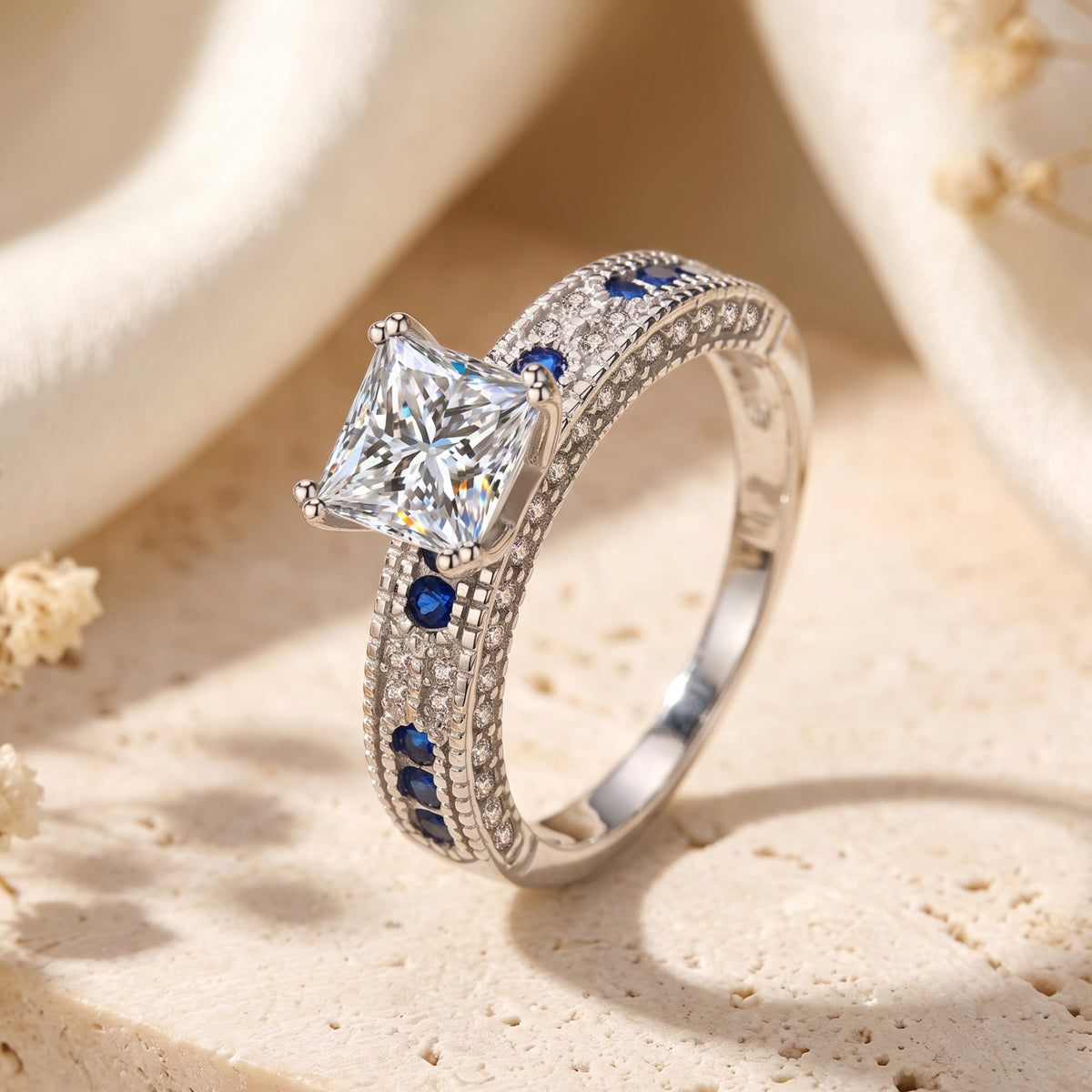 Angled view of a silver princess-cut CZ ring with blue sapphire side stones.