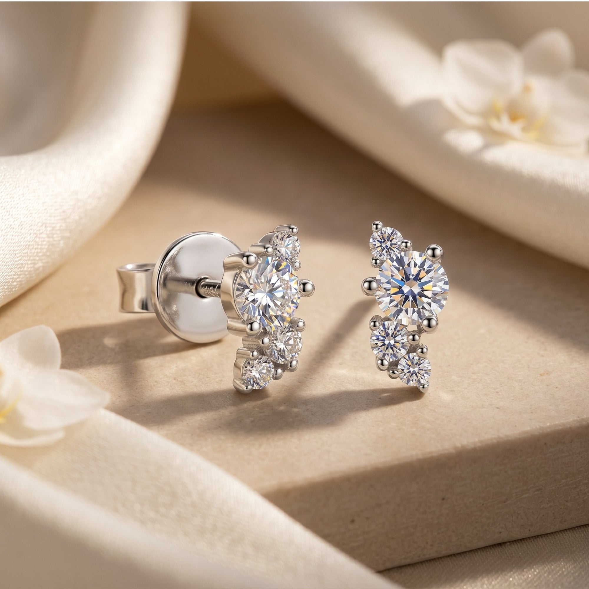Silver moissanite cluster earrings with round stones on a soft fabric background.