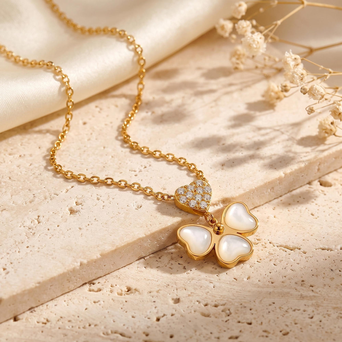 Angled view of a gold-tone mother-of-pearl butterfly necklace with a pavé heart, arranged on textured stone.