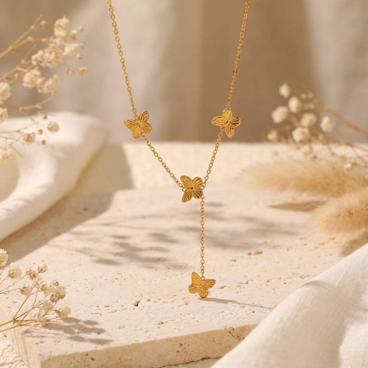 Gold-tone butterfly lariat necklace suspended upright, showing four butterfly charms on a fine chain.