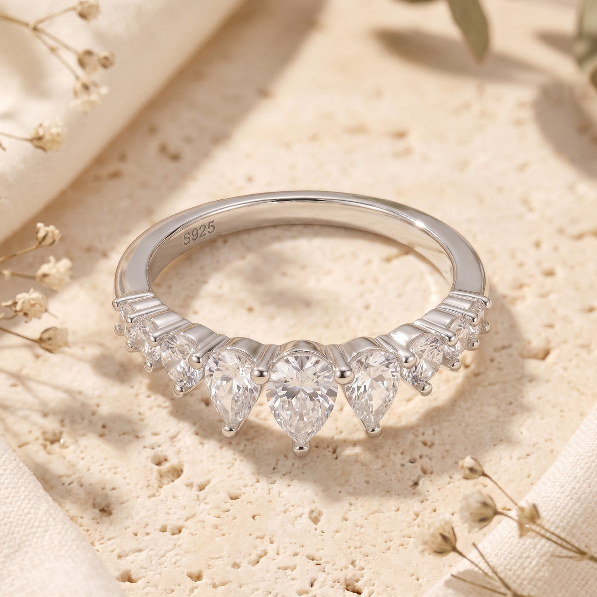 Front view of a silver tiara ring with a central pear-shaped stone and matching pear stones on each side.