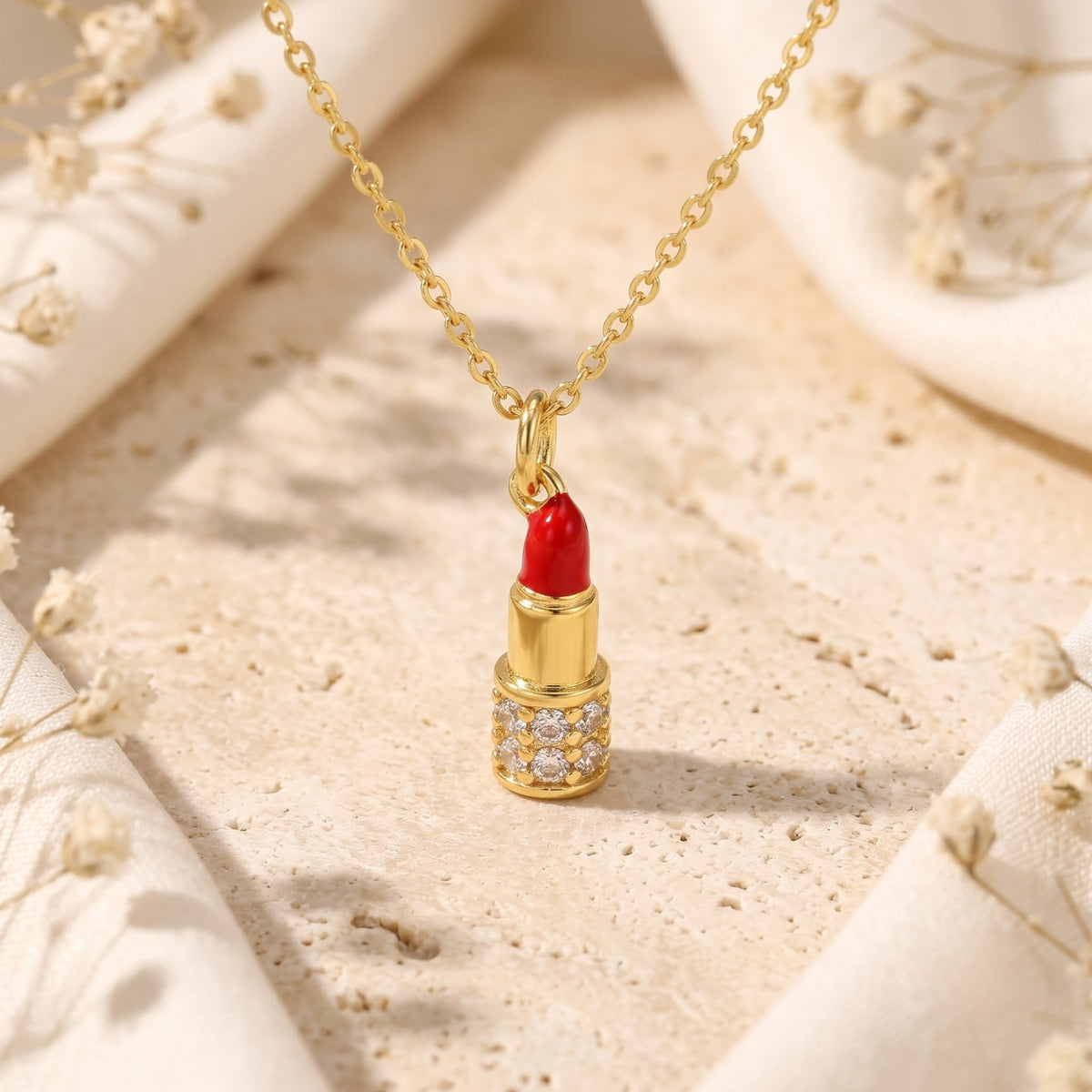 Centered close-up of the red enamel lipstick pendant with gold-tone details and simulated diamond accents.
