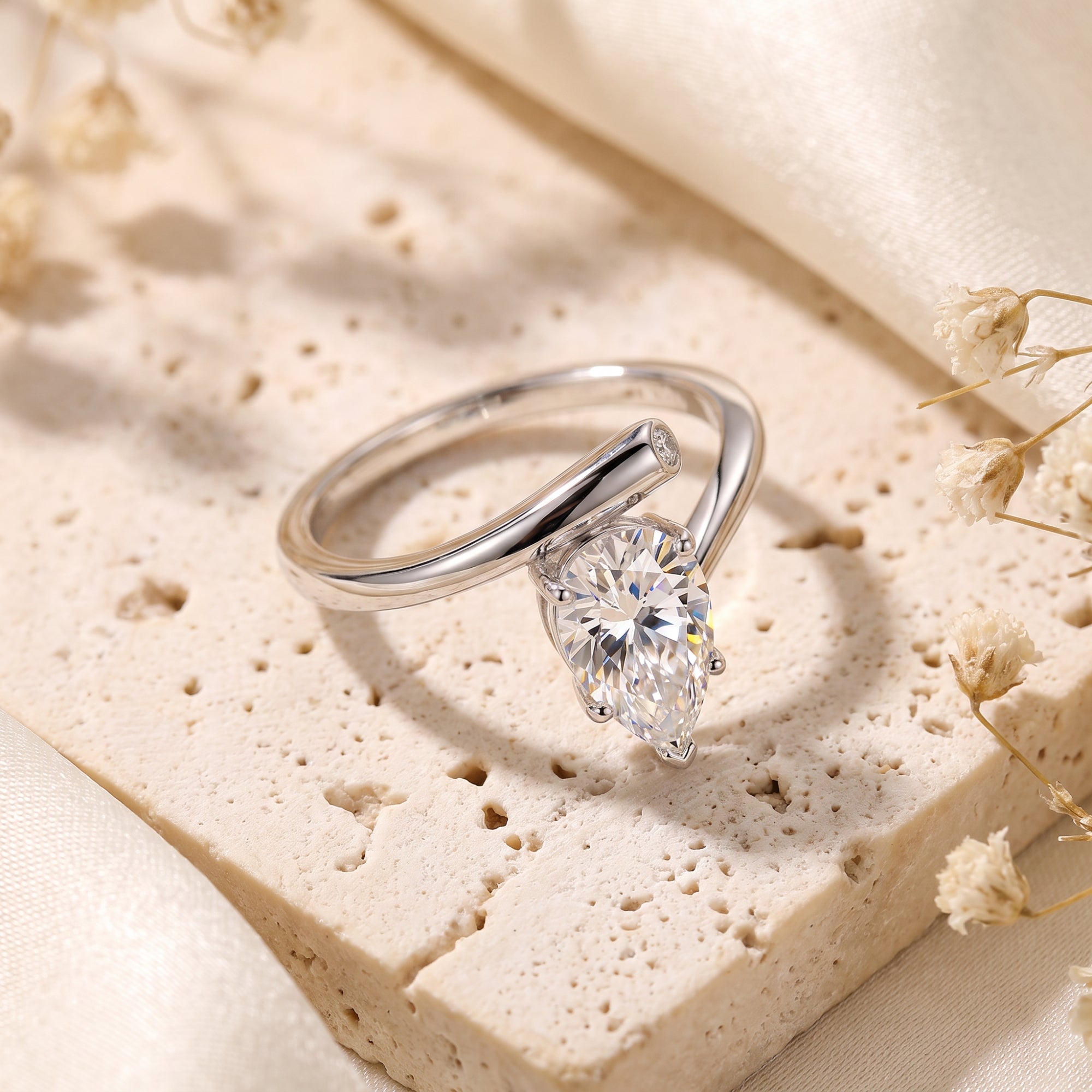 Macro view of a pear-cut simulated diamond in a sterling silver bypass setting.