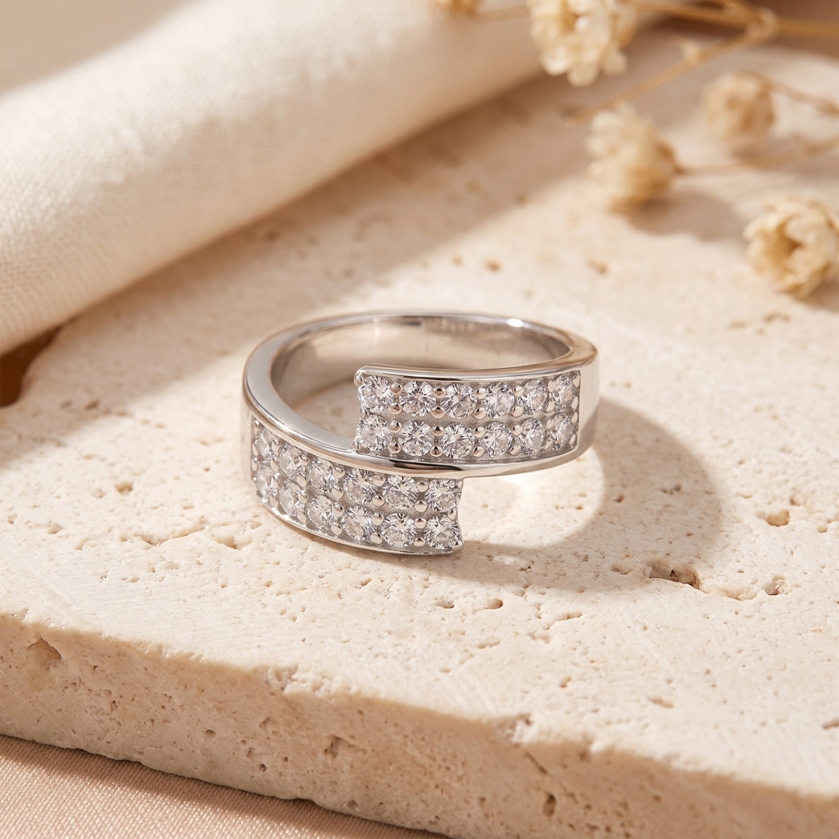 Front view of the silver Eldria bypass promise ring featuring two rows of round simulated diamonds on stone.