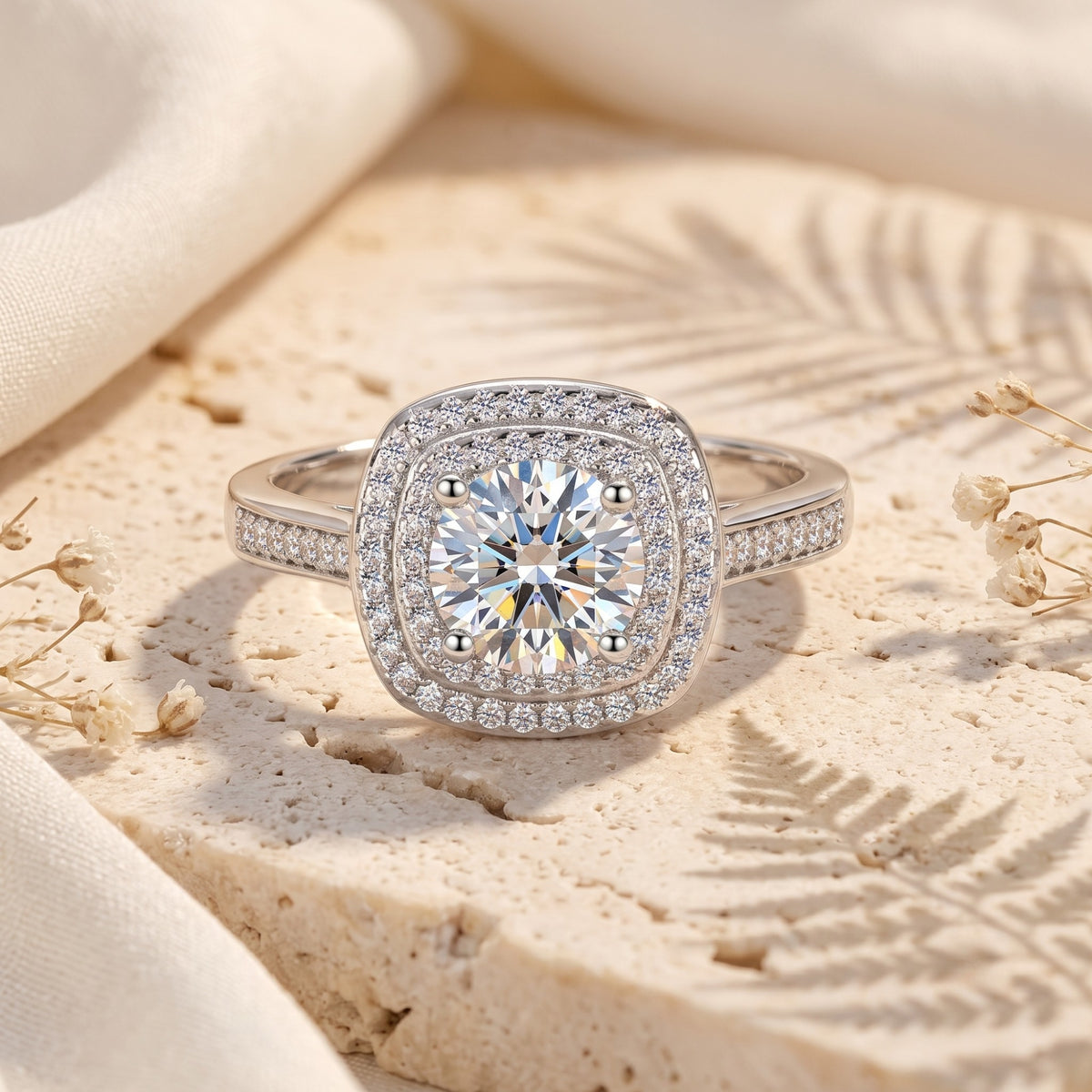 Front view of the silver double halo ring on textured beige stone with botanical shadows.