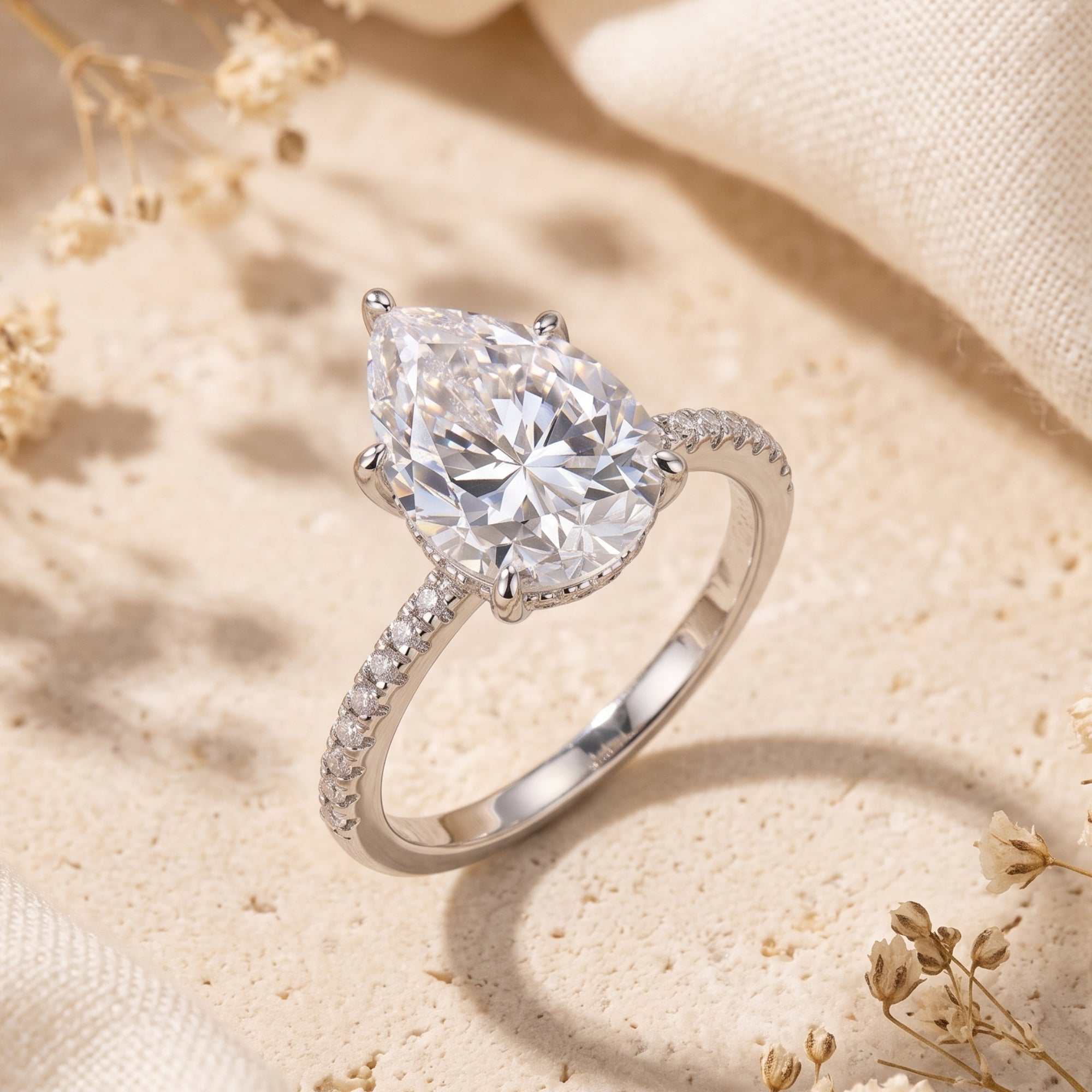 Angled view of the Dianora pear-cut simulated diamond ring in sterling silver on a neutral stone background.