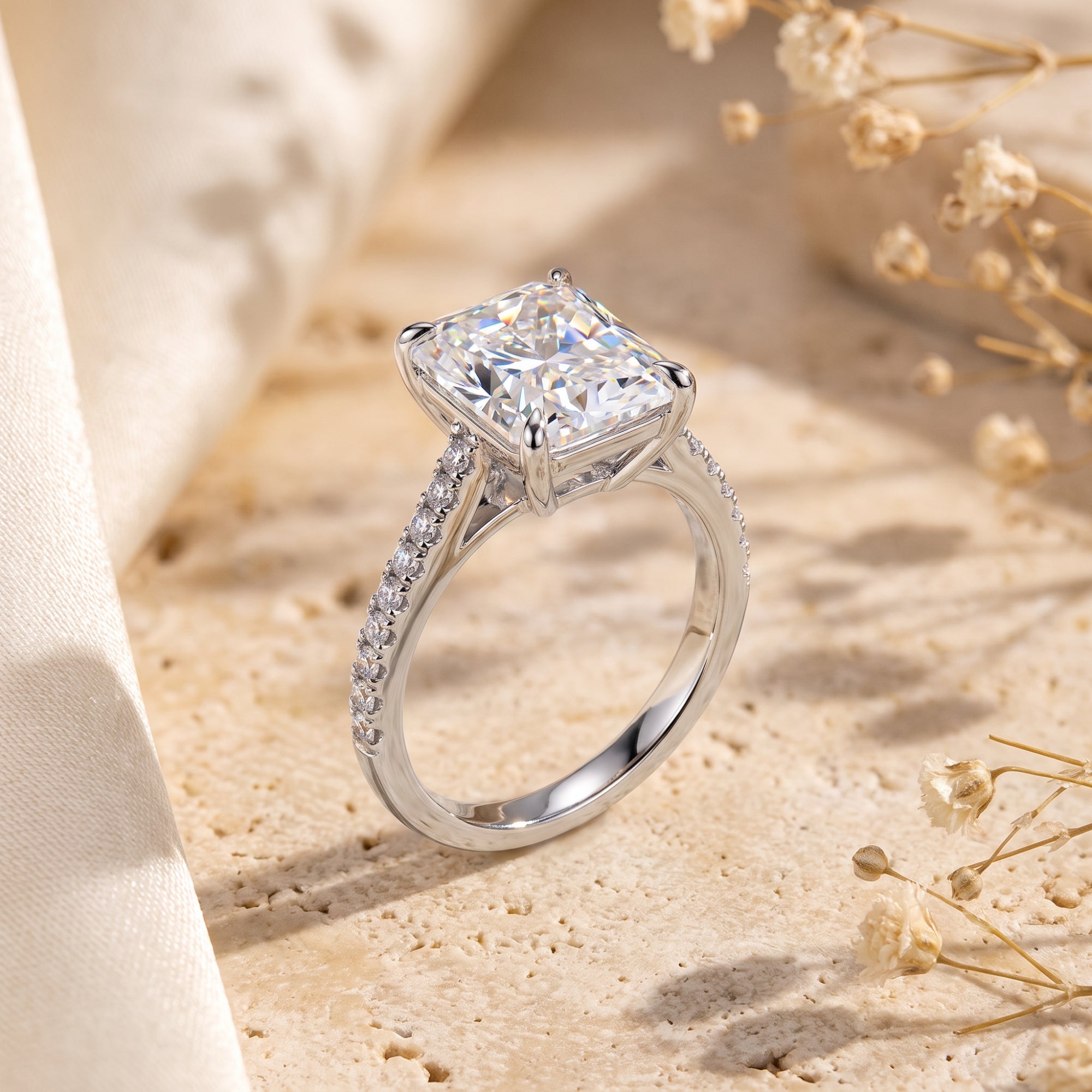 Side profile of the radiant-cut CZ sterling silver Claudette ring on a stone surface with dried flowers.