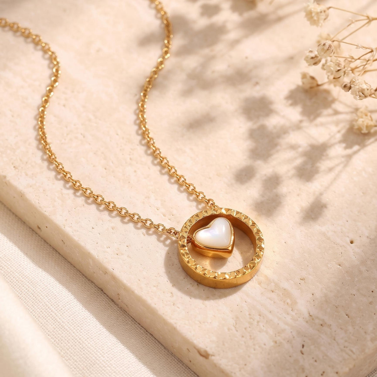Detail of 18K gold finish Rosetta pendant with heart-cut mother of pearl and textured circle.