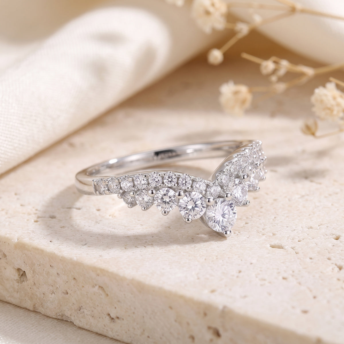 Close-up of a silver wishbone ring featuring precision-cut cubic zirconia stones on a textured base.