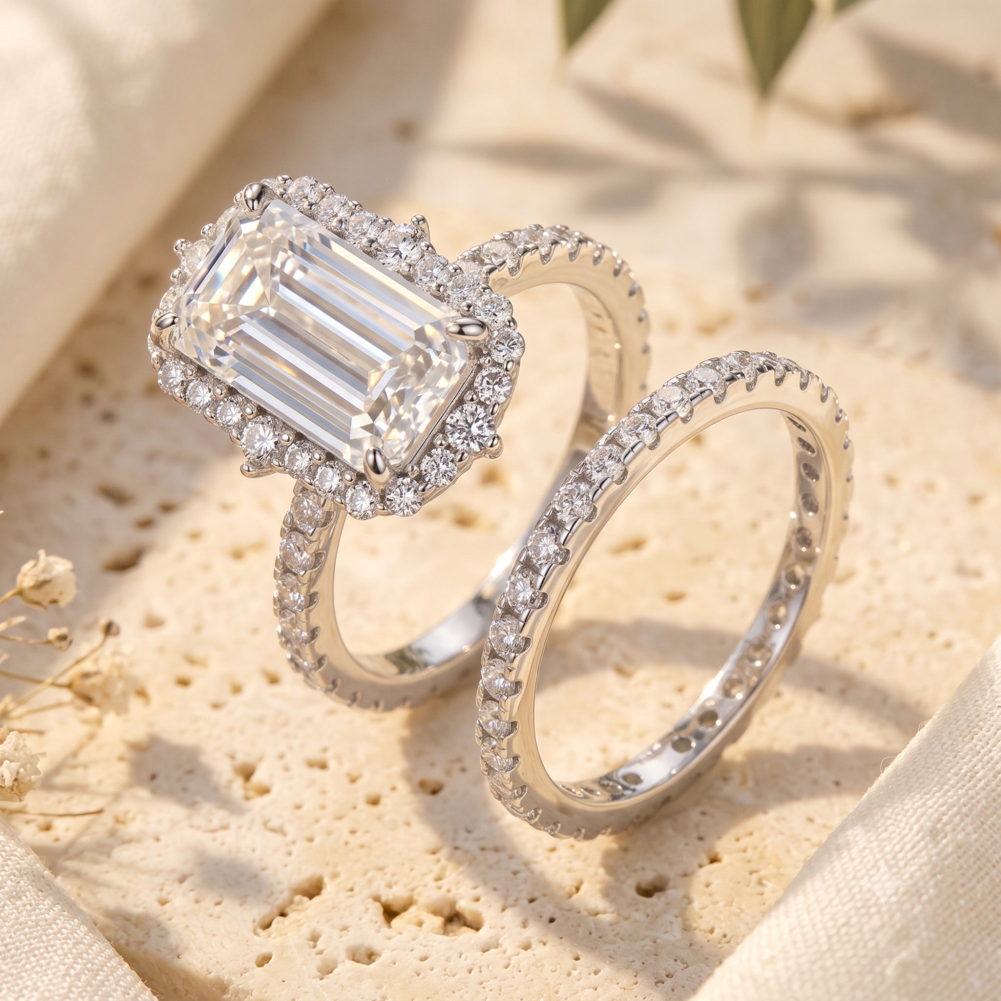 Macro view of silver halo ring set with emerald-cut simulated diamond and pavé eternity band.