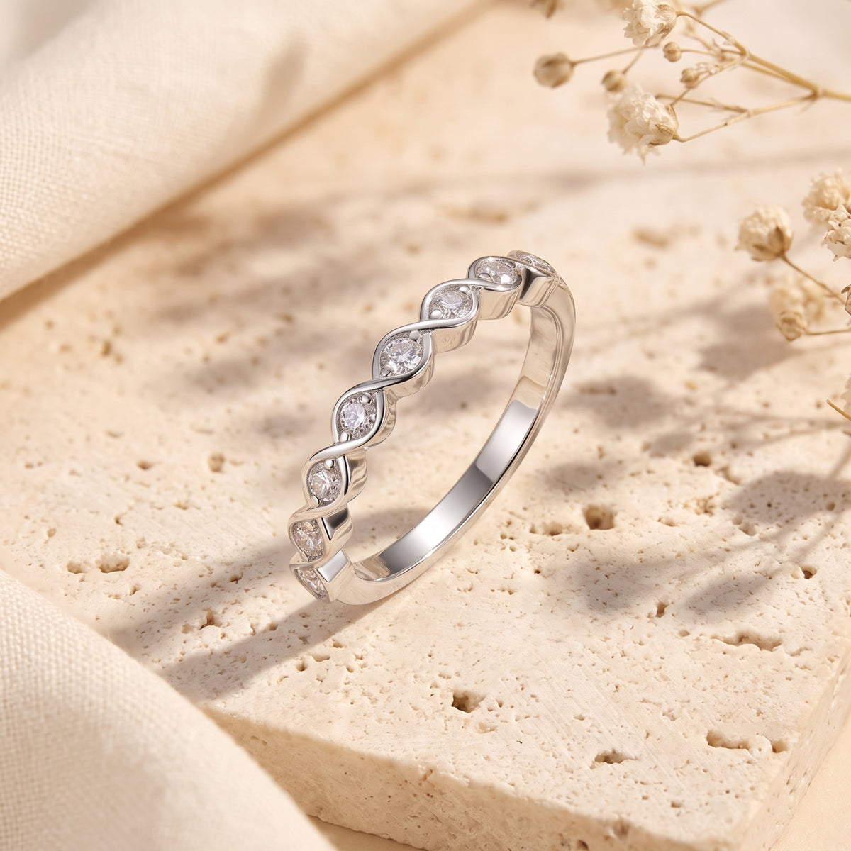 Macro view of the Amandelle sterling silver ring's wave silhouette and hand-set round-cut simulated diamonds.