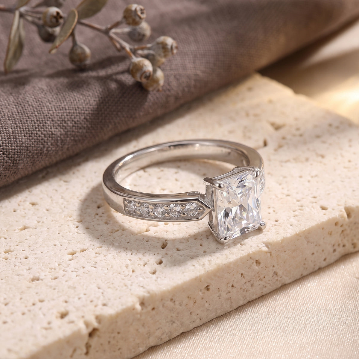 Side view of the radiant-cut simulated diamond sterling silver ring on a textured stone base.