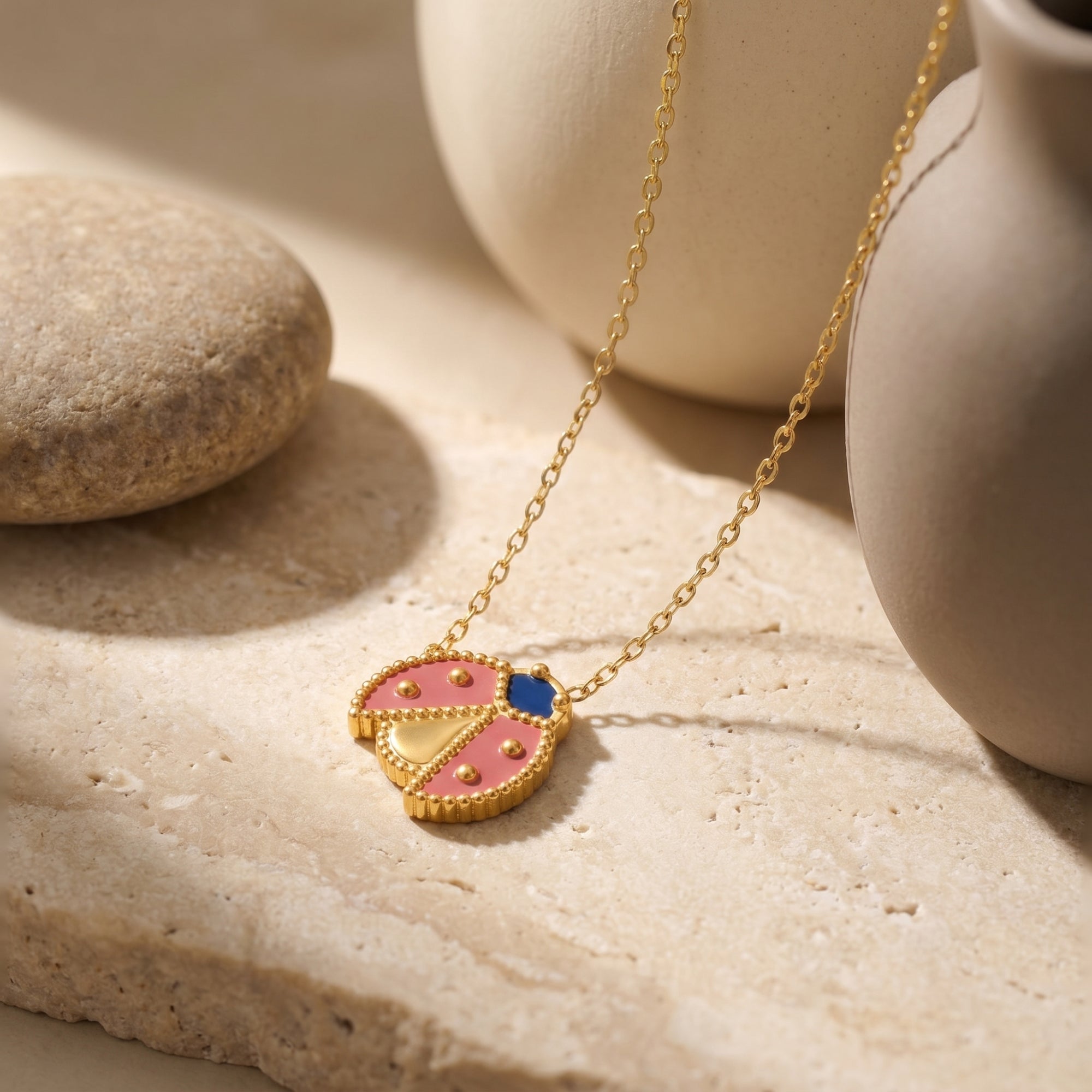 Macro view of a gold ladybug pendant with red and blue enamel details.
