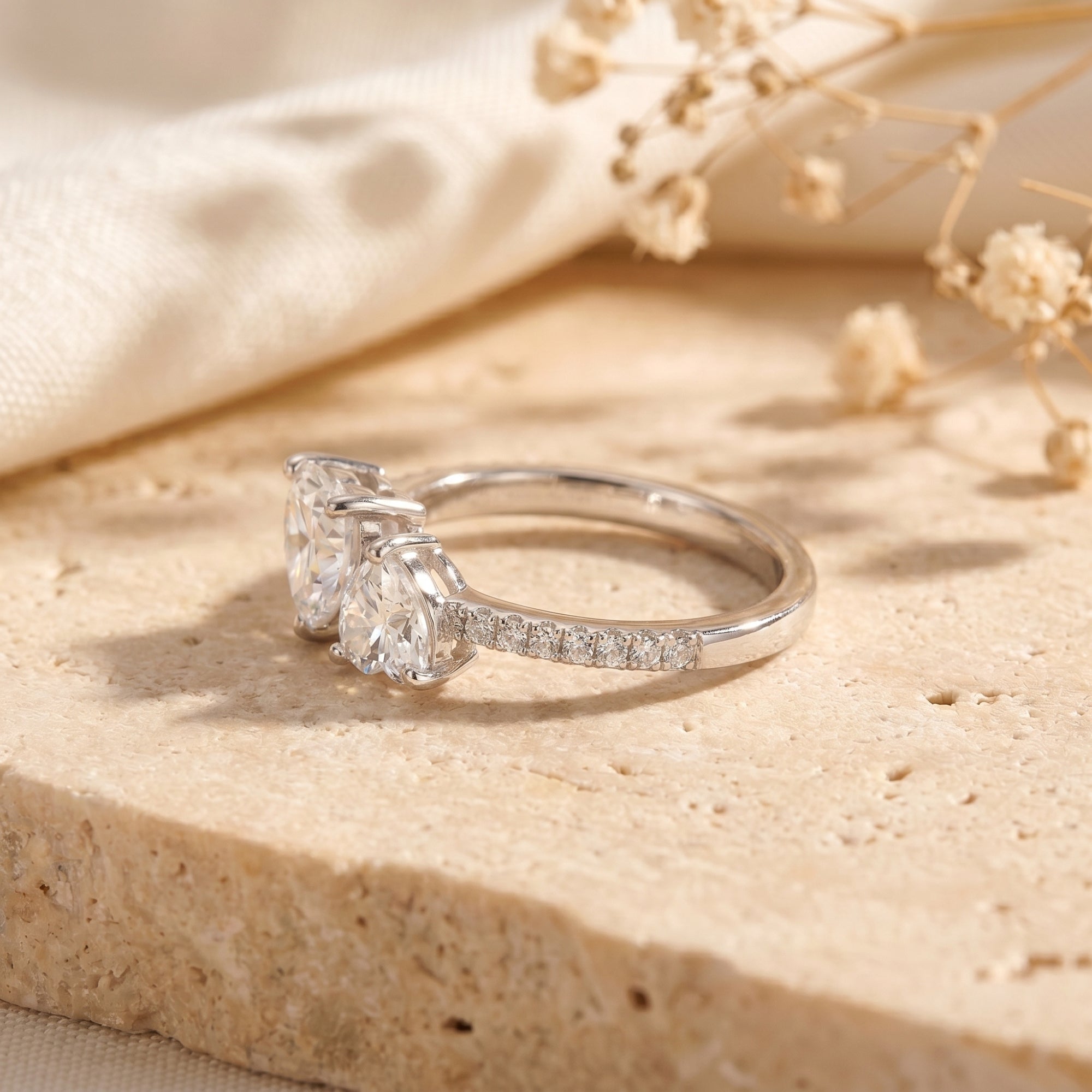 Side view of a silver moissanite ring showing heart-cut stone settings and pavé band details.