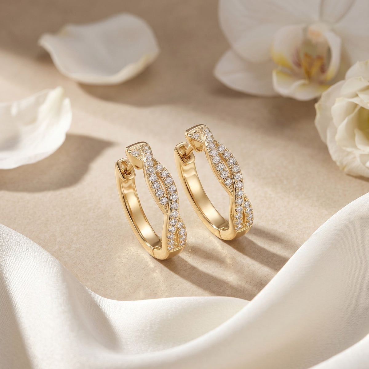 Gold moissanite twisted hoop earrings on stone with floral accents.