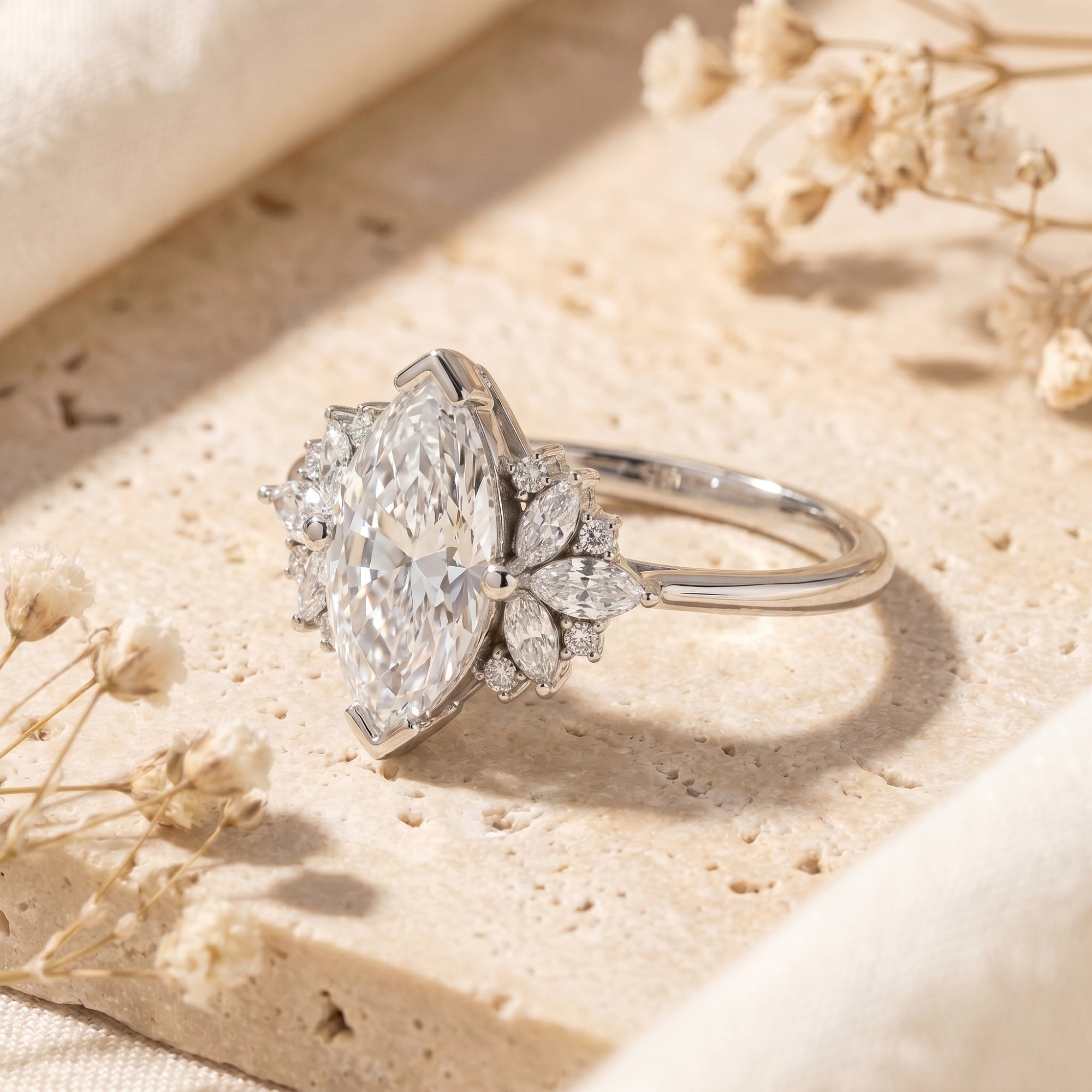Side view of a silver marquise moissanite ring showing the intricate cluster setting on a stone surface.