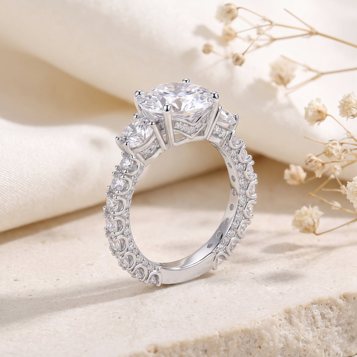 Side profile of the three-stone ring, showing the prong basket setting, pave undercarriage, and embellished band.