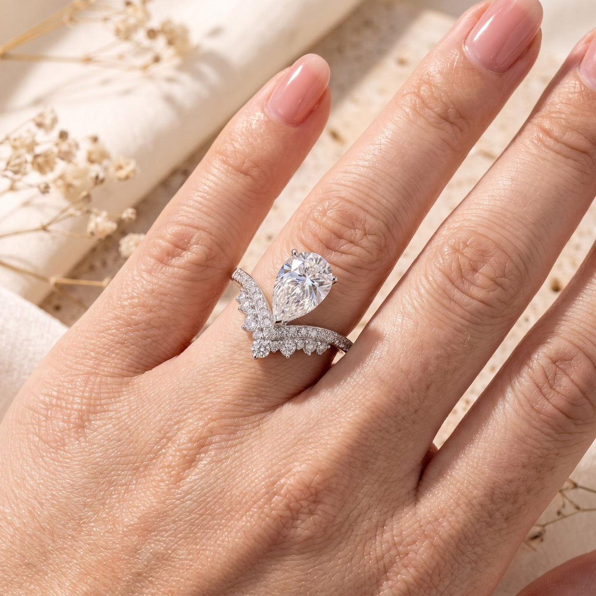 Sterling silver wishbone ring with pear-cut simulated diamond shown on a hand.