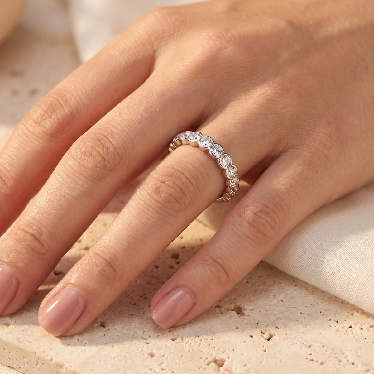 Side view of the Zarielle simulated diamond bezel eternity ring in sterling silver worn on a model's hand.