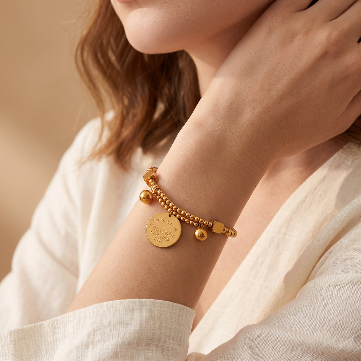 Wider view of a model wearing the gold-tone double-strand beaded charm bracelet.