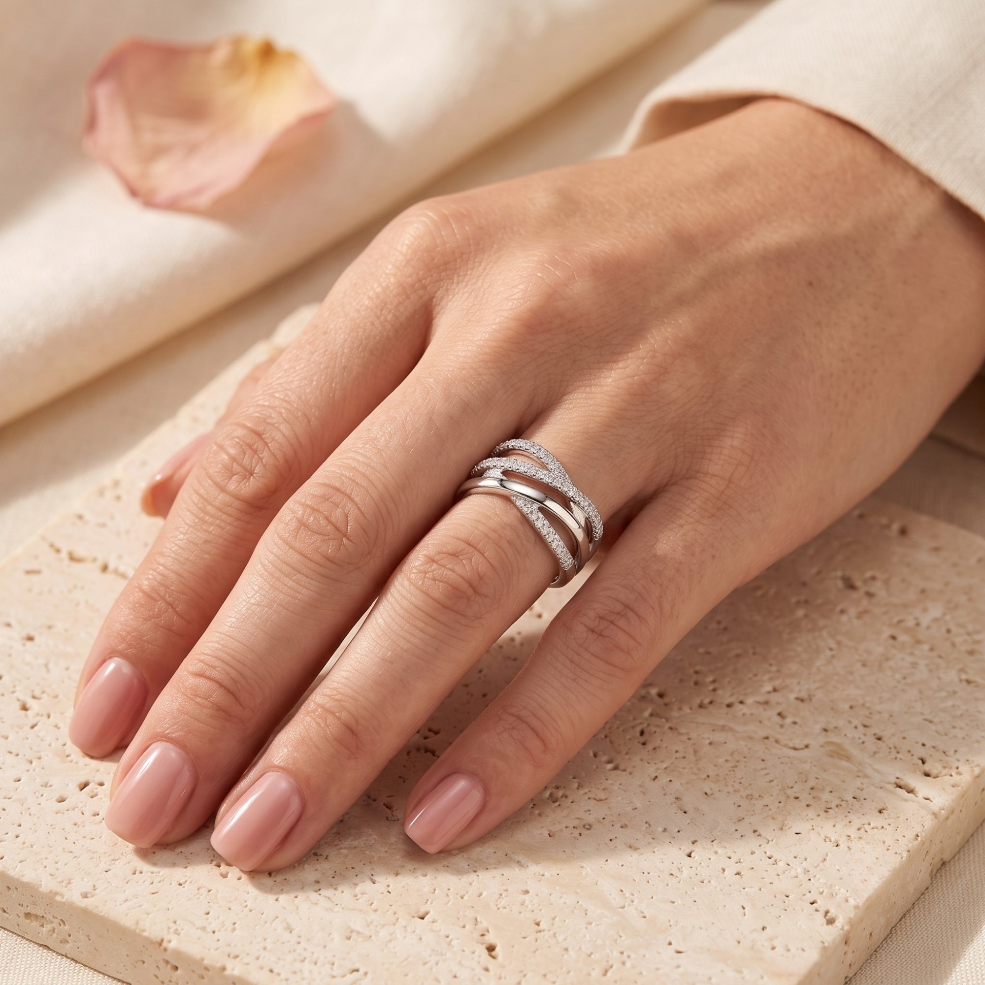 Silver crossover ring with simulated diamonds on a hand for scale.
