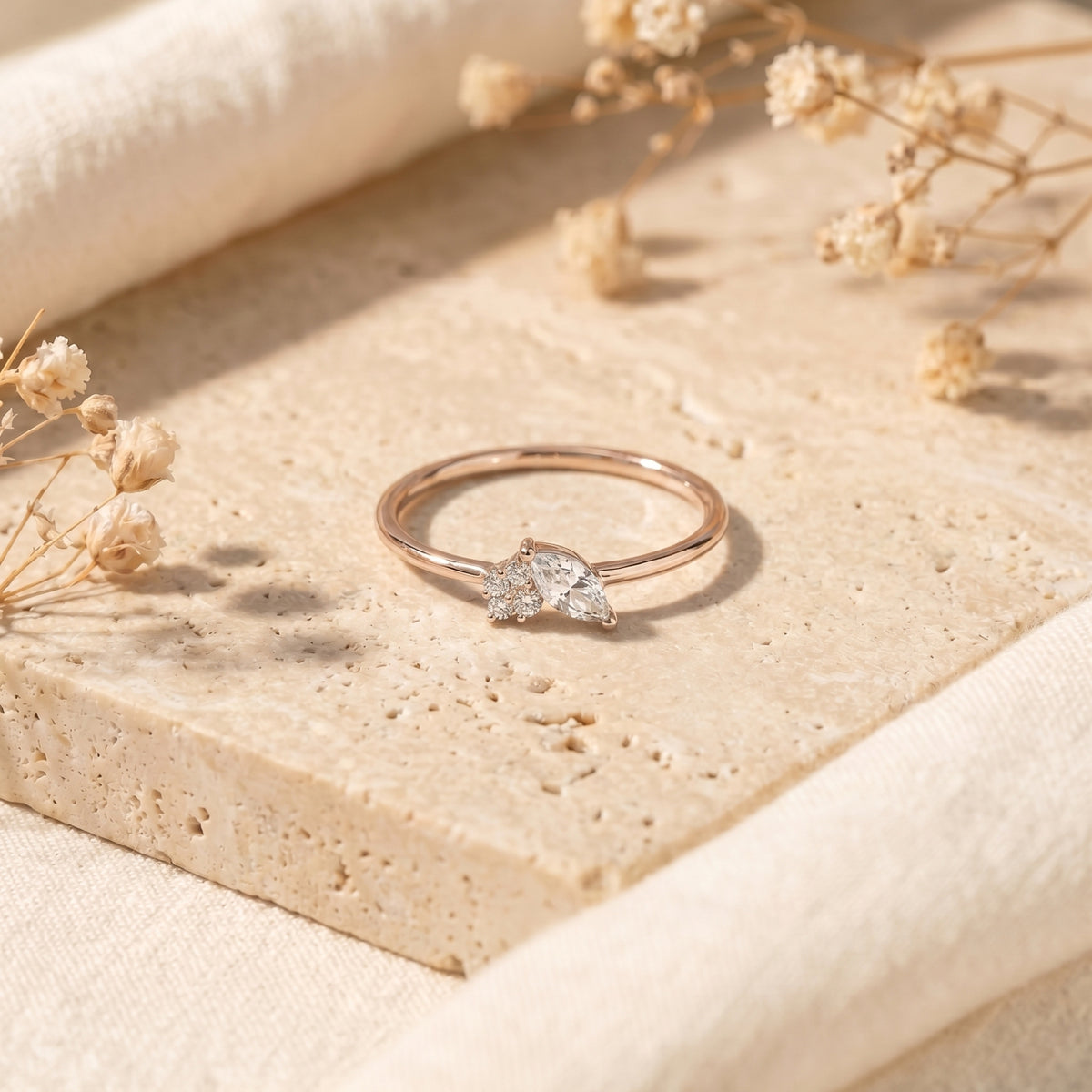 Rose gold marquise moissanite ring on stone with floral accents.
