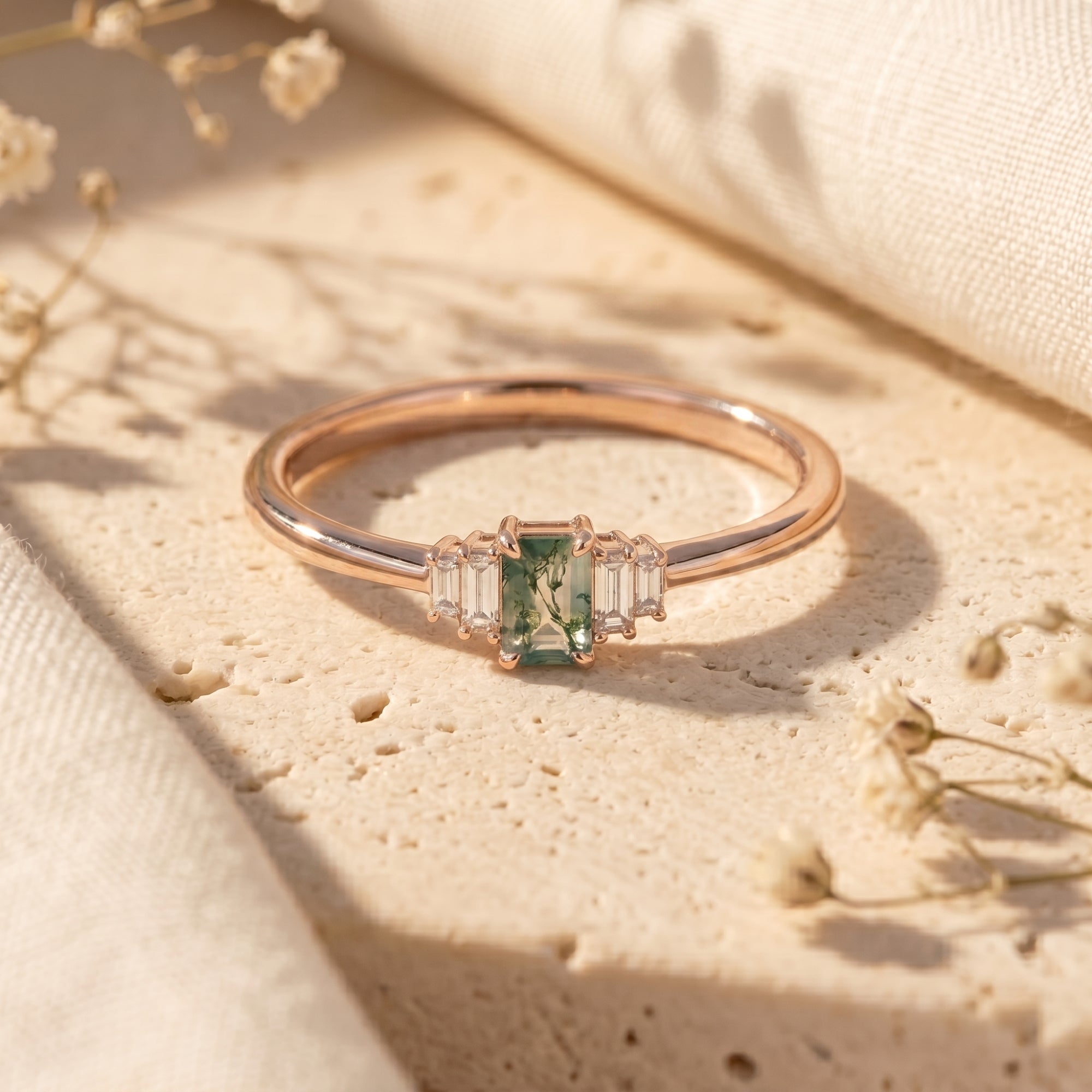 Rose gold green moss agate ring featuring an emerald-cut stone and baguettes in a lifestyle setting.