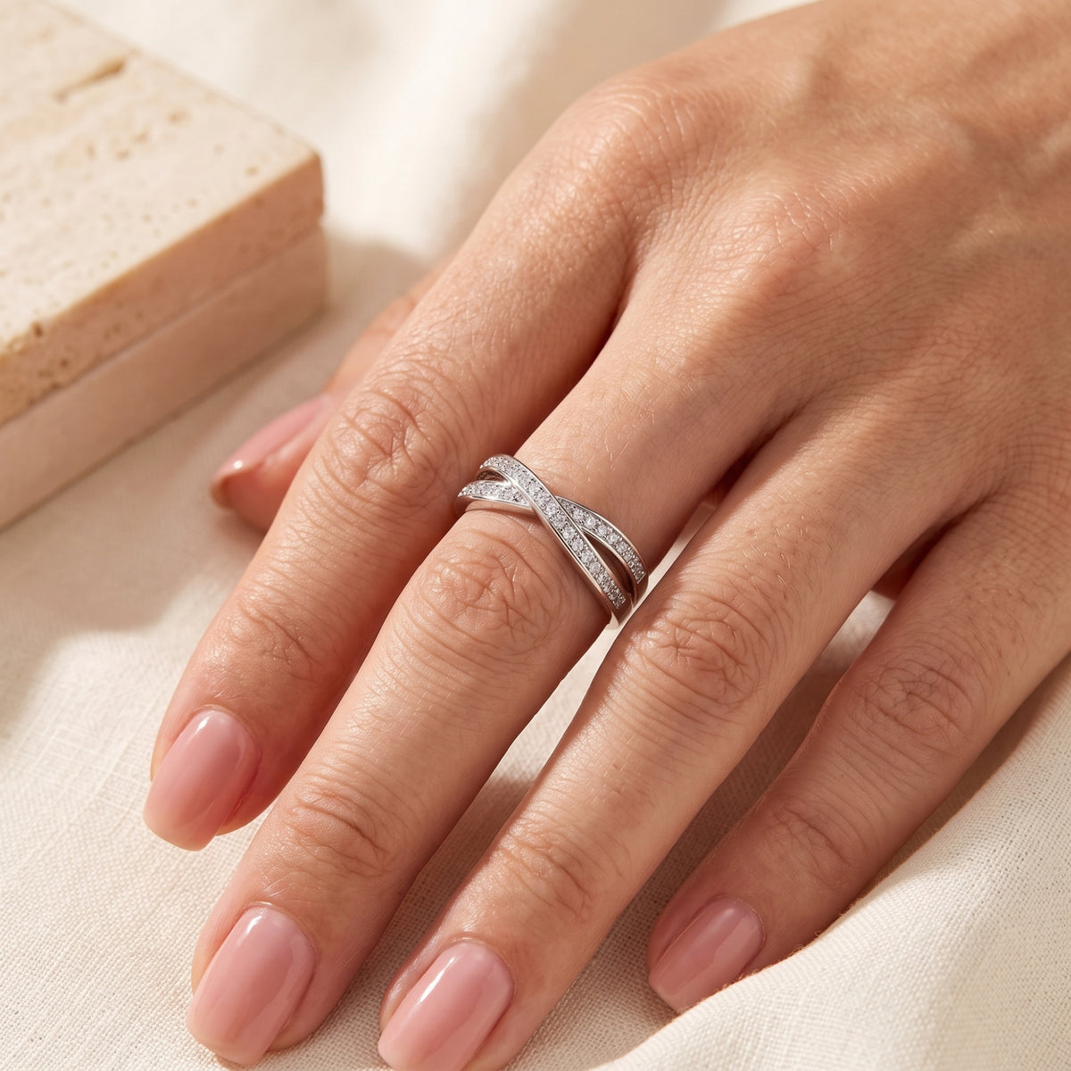 Silver crossover ring with cubic zirconia on a hand showing scale and fit.