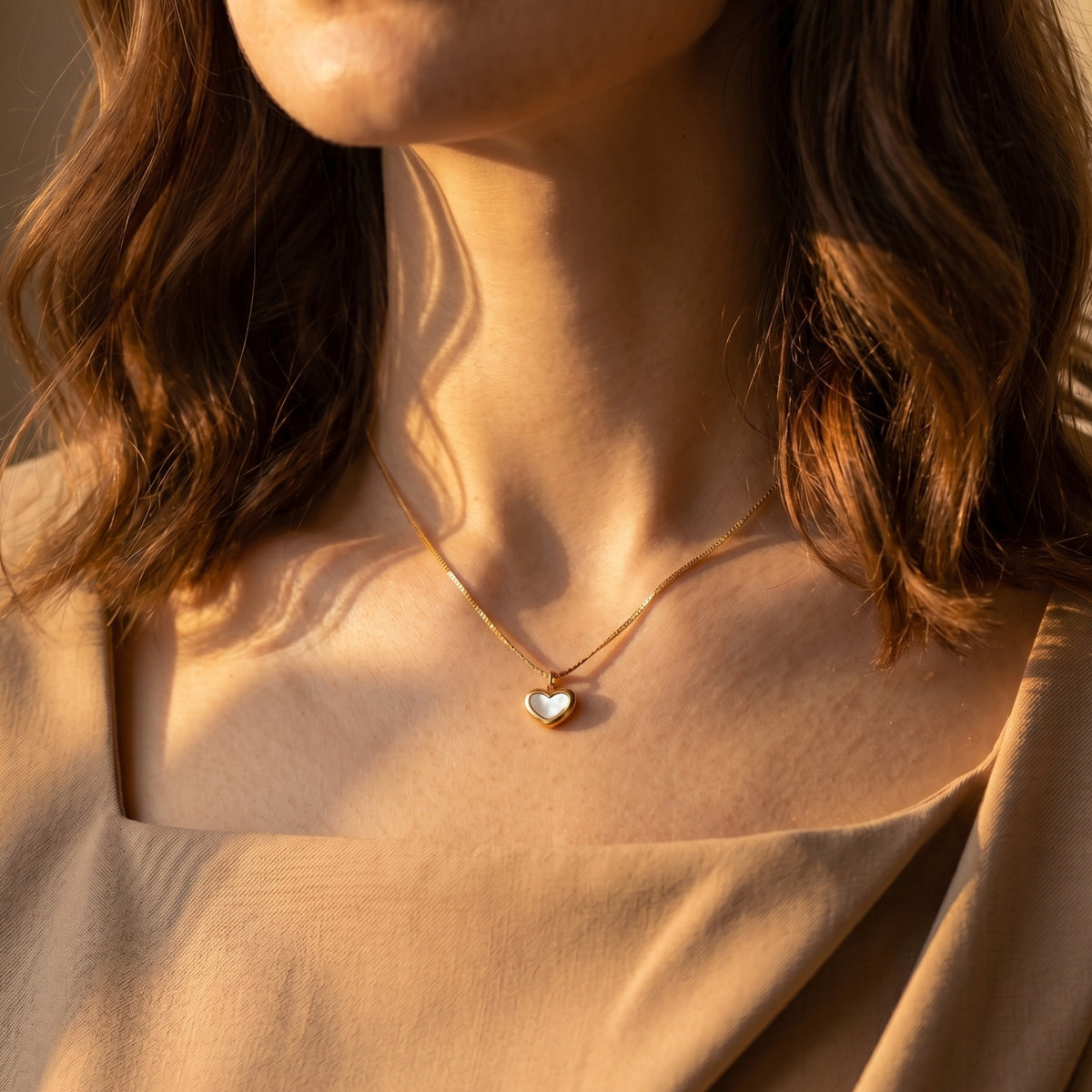 Model wearing the gold heart necklace with white inlay in warm, natural sunlight.